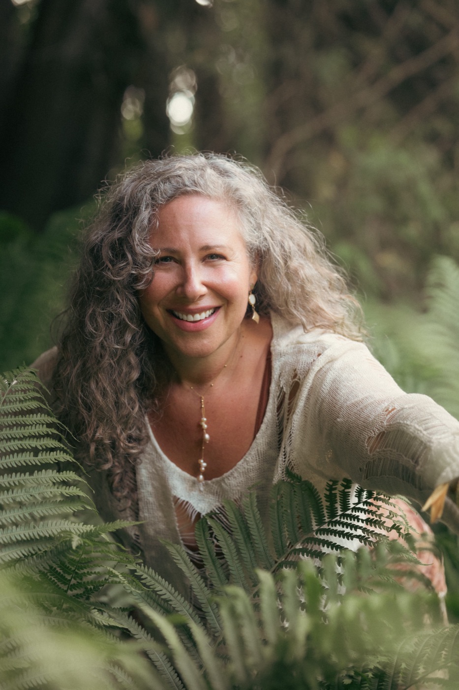 Jaime Verk smiling among ferns in a forest